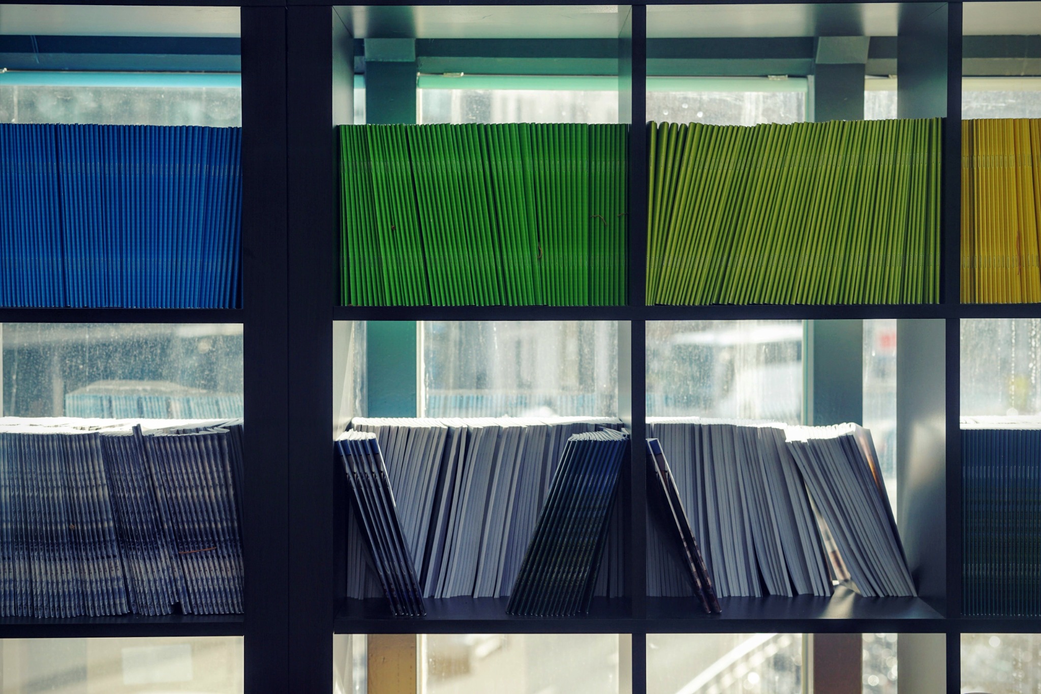 Rows of coloured folders and paper files on shelves.